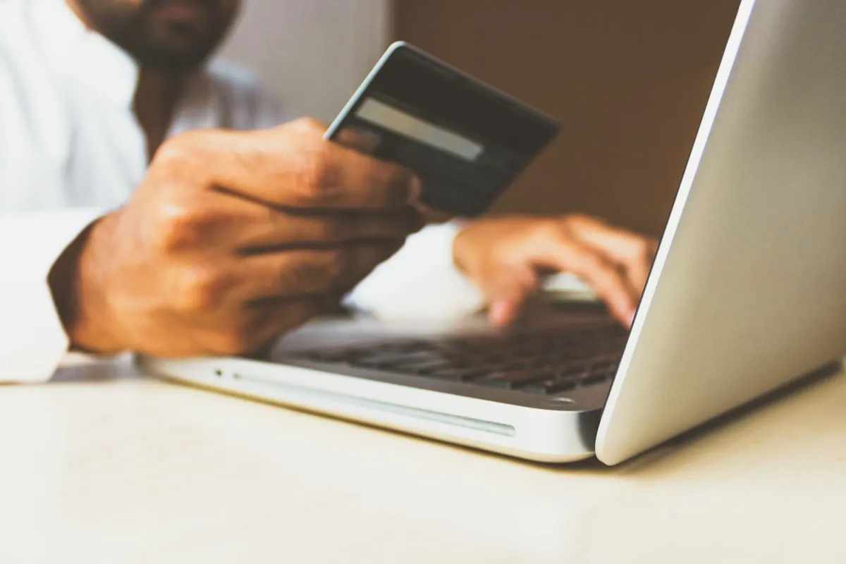 A person shopping online with a credit card and laptop - the moment where instant support can make or break a sale